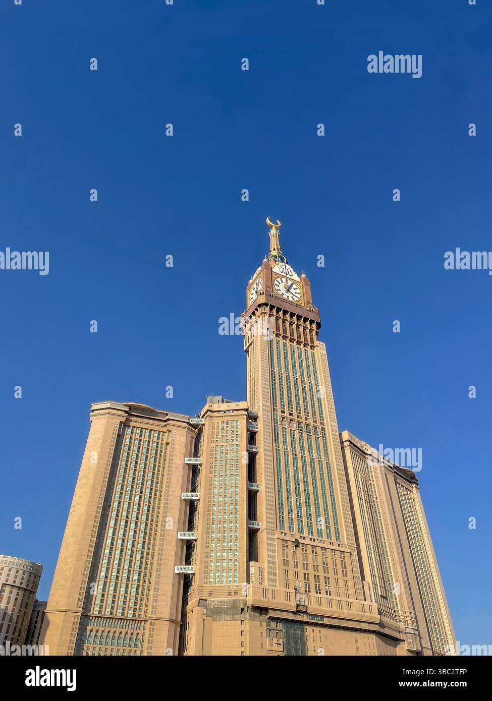 Makkah Uhrenturm leuchtet hell unter klarem, tageshellblauem Himmel. Dieses Foto wurde aus Makkah, Saudi-Arabien, aufgenommen. Stockfoto