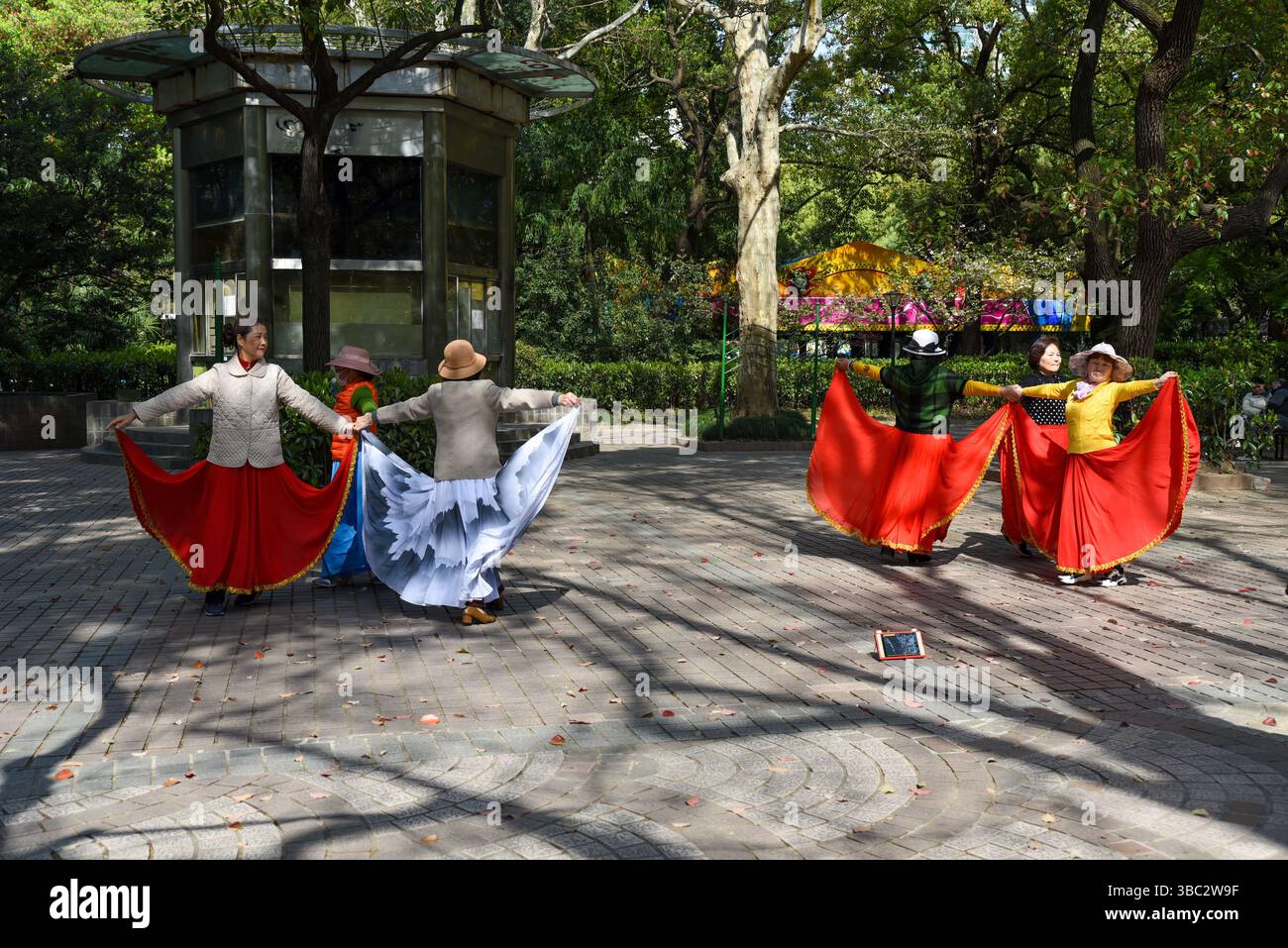Shanghai, China - 1. April 2025: Ältere chinesische Frauen üben an einem sonnigen Tag traditionellen Tanz mit bunten Stoffen im People’s Park Stockfoto