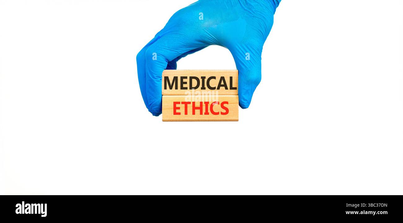 Medizinethik-Symbol. Konzeptworte medizinische Ethik auf schönen Holzblöcken. Arzthand in blauem Handschuh. Schöner weißer Hintergrund. Medizinische Heilung Stockfoto