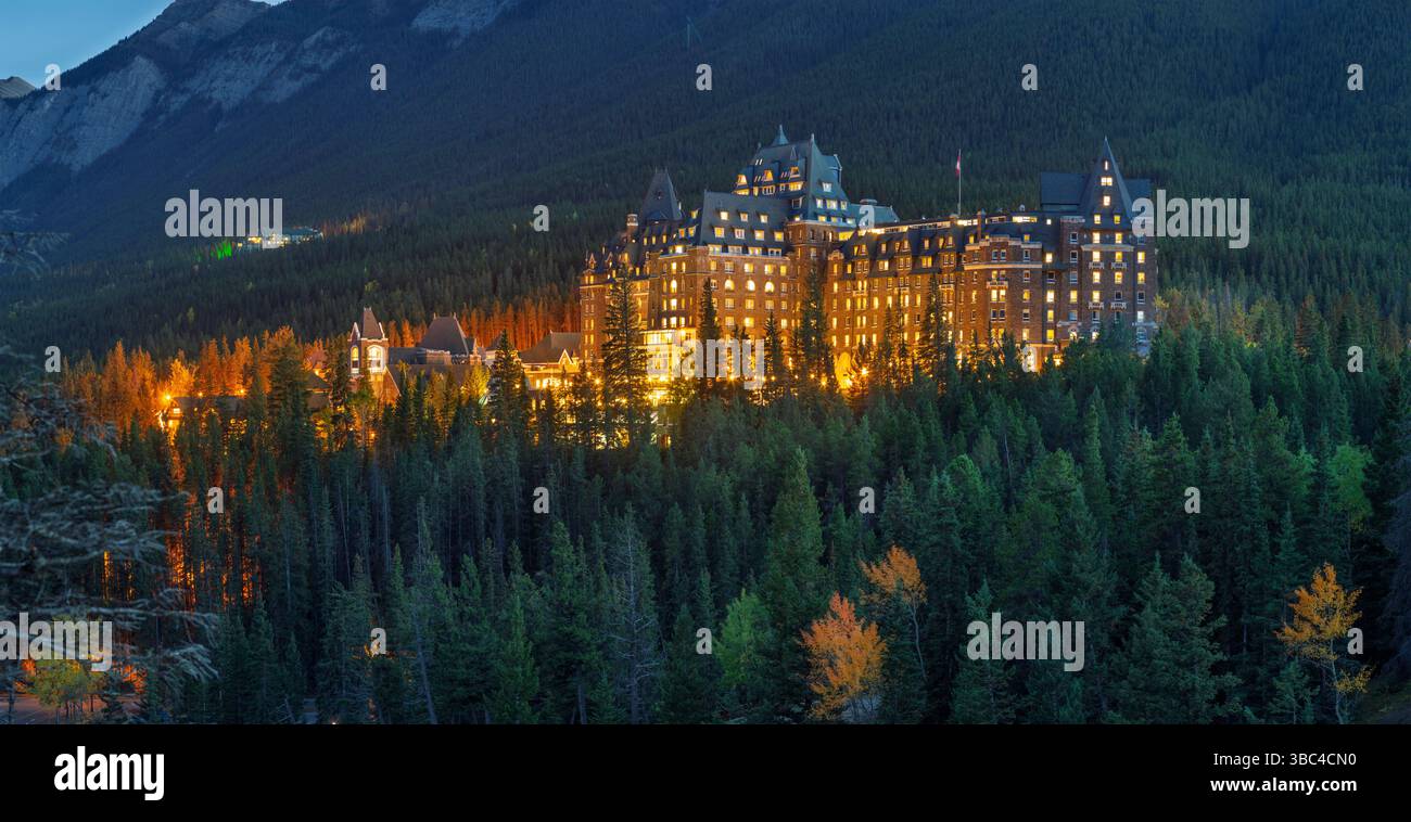 Das Fairmont Banff Springs Hotel, das „Schloss in den Rockies“, leuchtet im Abendlicht, umgeben von dichtem Wald. Stockfoto