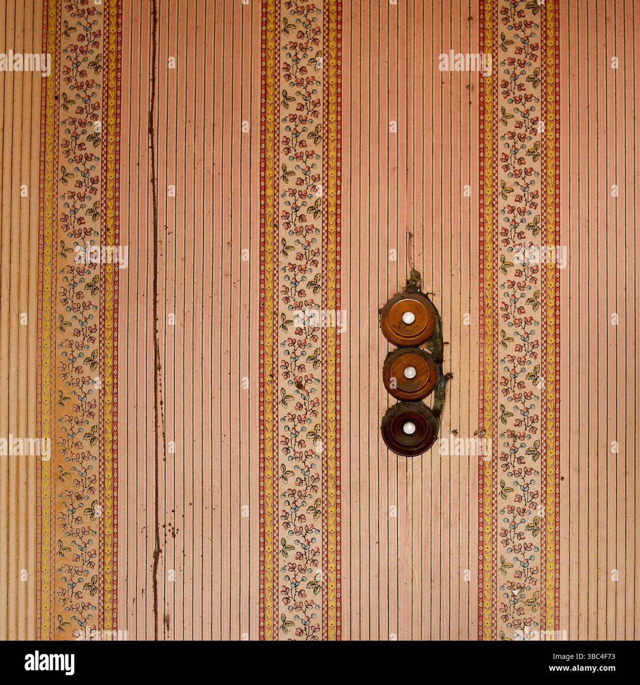 Die Wände eines alten Gebäudes sind mit komplizierten Blumenmustern und bezaubernden Streifen geschmückt, während drei runde Knöpfe aus alten Gebäuden wechseln Stockfoto