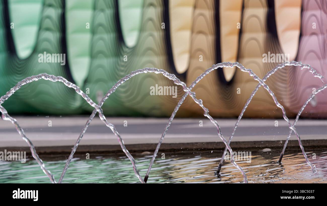 Streamen Sie Wasserbögen Über Den Reflektierenden Pool Mit Lebendigem Hintergrund Stockfoto