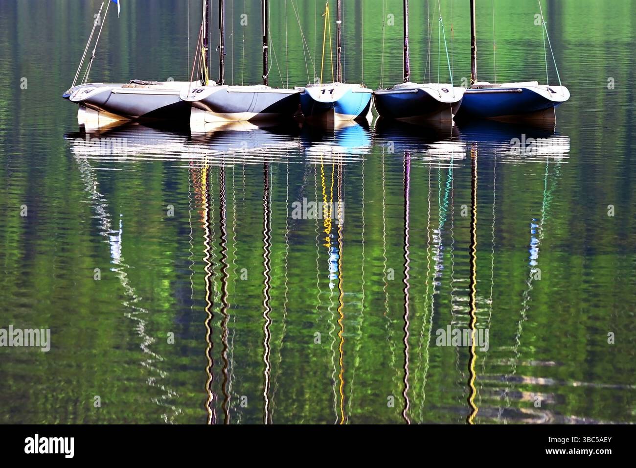 Kleine Segelboote mit Reflexionen im Wasser, die am Bohinj-See, dem Triglav-Nationalpark, den Julischen Alpen, Slowenien vor Anker gehen Stockfoto Kleine Segelboote mit Reflexionen im Wasser, die am Bohinj-See, dem Triglav-Nationalpark, den Julischen Alpen, Slowenien vor Anker gehen Stockfoto
