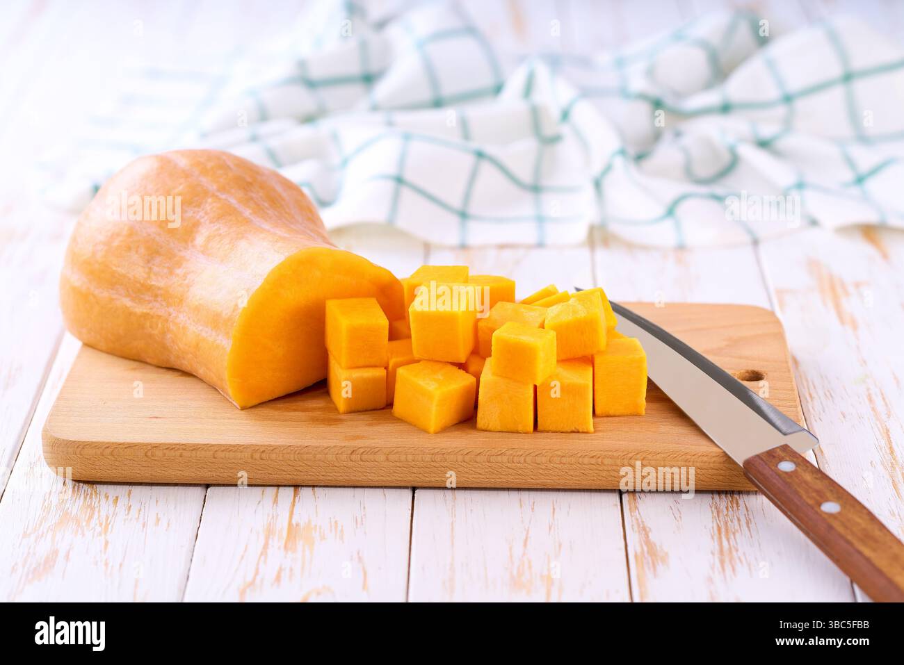 Gewürfelter Butternusskürbis auf hölzernem Schneidebrett, selektiver Fokus. Stockfoto