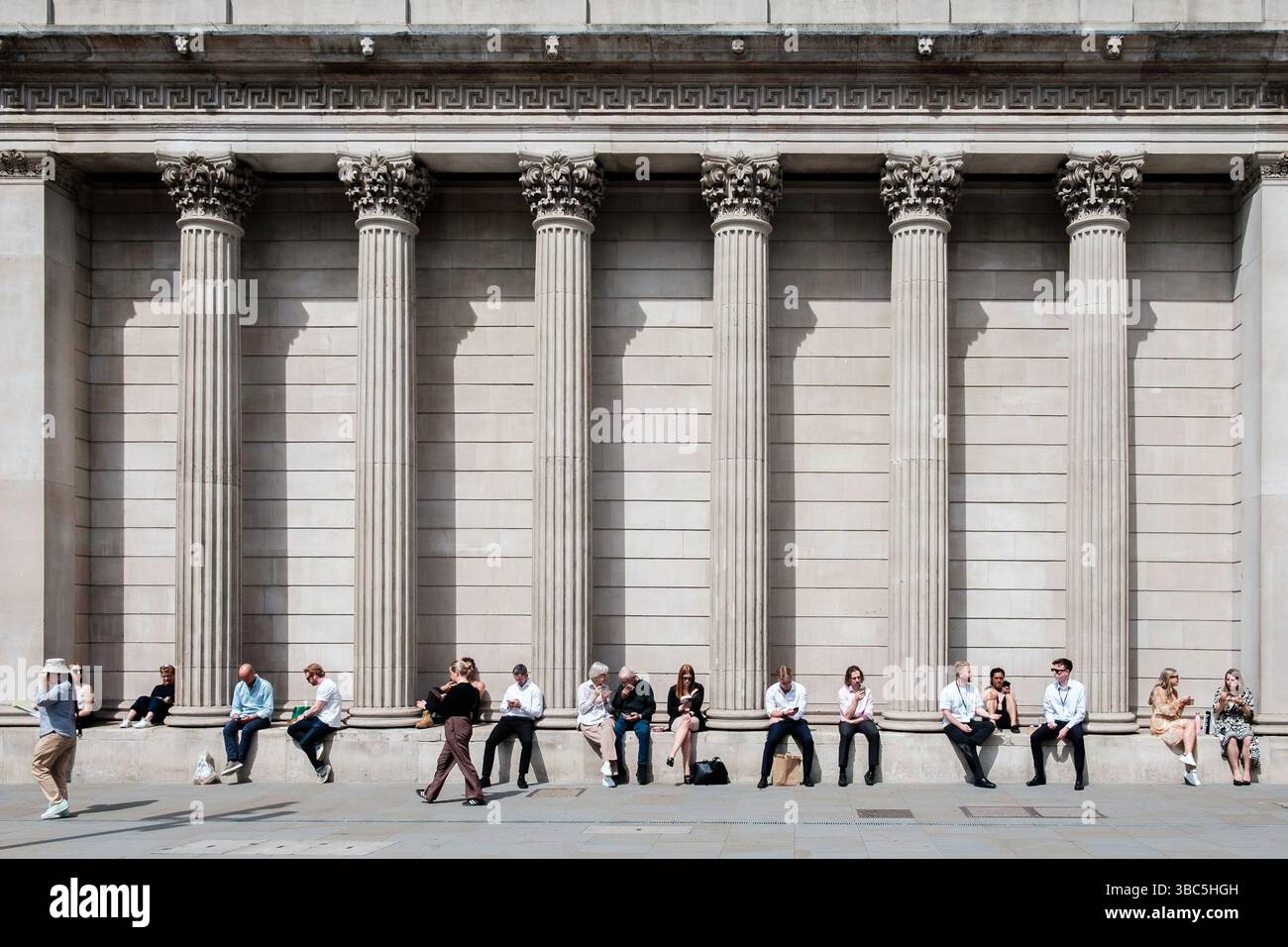 Menschen, die die Frühlingssonne in London genießen, sitzen am Fuße der Säulen der Bank of England, City of London, Großbritannien Stockfoto Menschen, die die Frühlingssonne in London genießen, sitzen am Fuße der Säulen der Bank of England, City of London, Großbritannien Stockfoto
