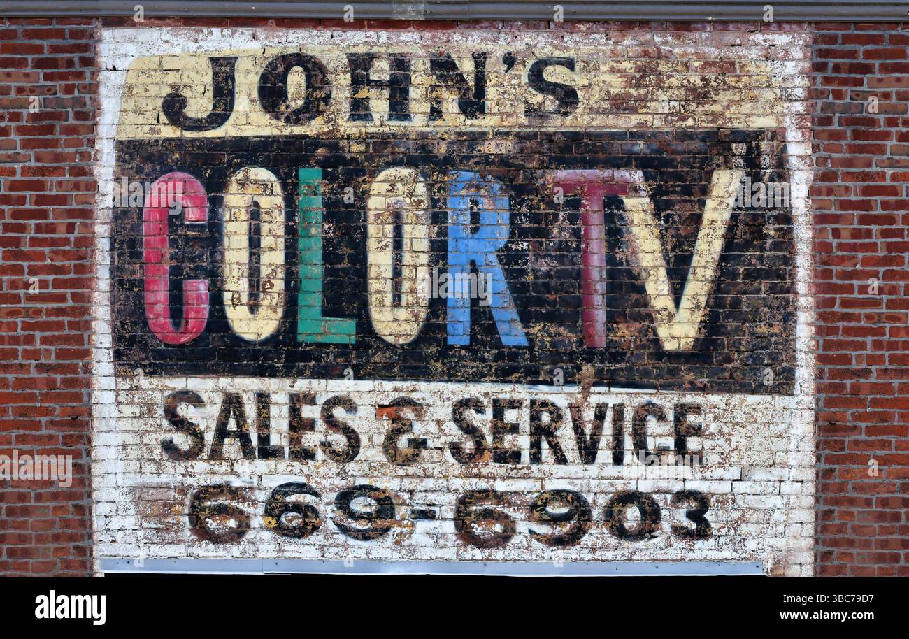 Eine alte TV-Reparaturanzeige, die auf die Backsteinwand eines Gebäudes gemalt ist Stockfoto