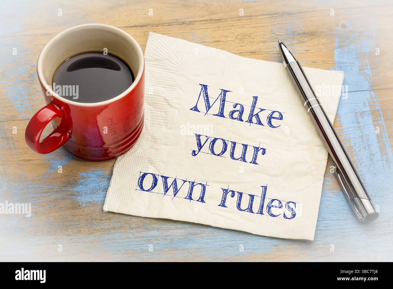 Machen Sie Ihre eigenen Regeln – Handschrift auf einer Serviette mit einer Tasse Espresso Stockfoto