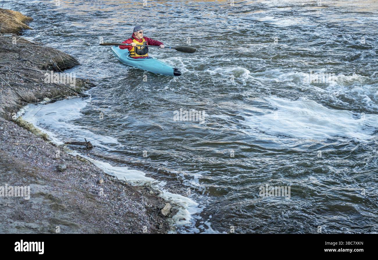 Männliche Kajakfahrer paddeln flussaufwärts des turbulenten Flusses mit einem schnellen Fluss Stockfoto