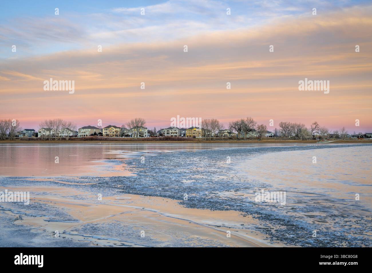 Eiskalter See nach Sonnenuntergang mit Häusern am Ufer - Boyd Lake im Norden von Colorado Stockfoto