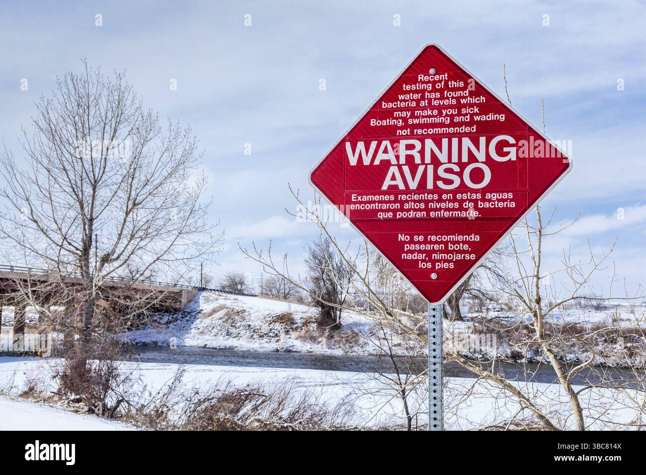 Warnschild für Wasserverschmutzung auf Englisch und Spanisch - South Platte River in Brighton, Colorado Stockfoto