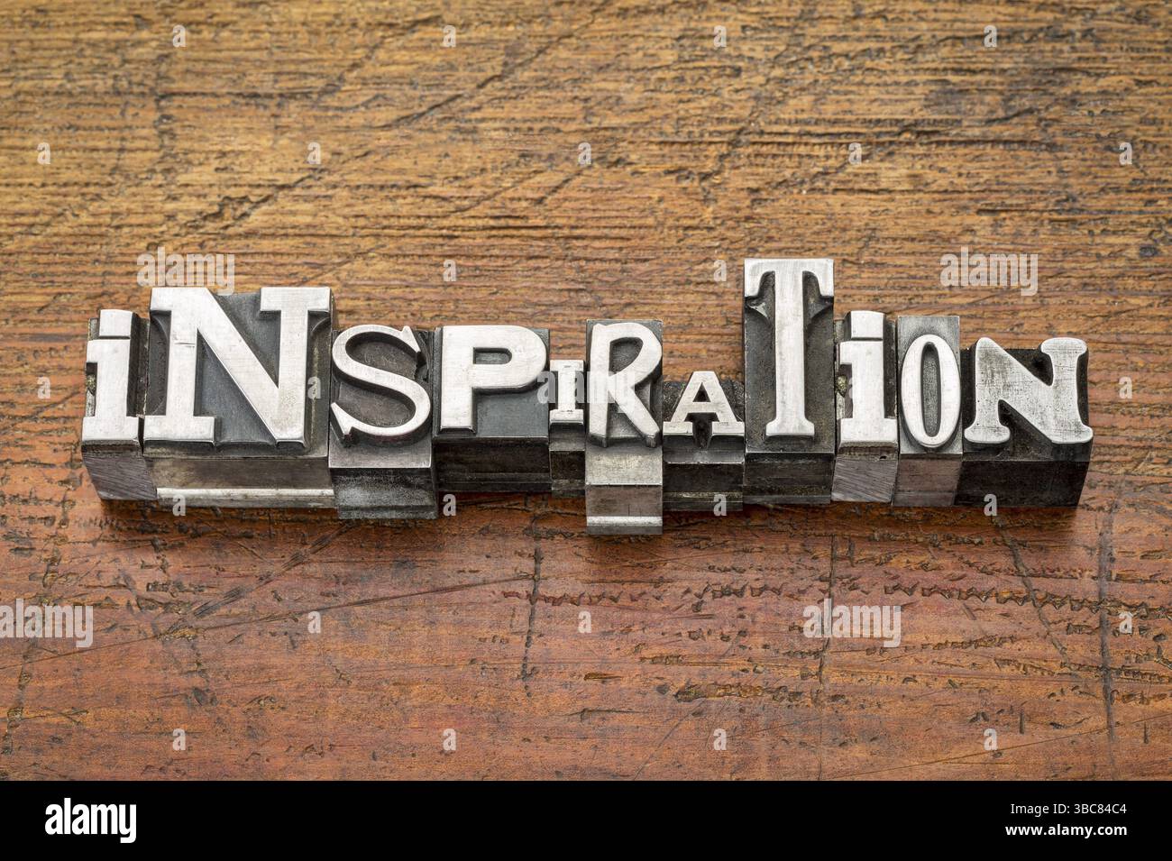 Inspirationswort in Vintage-Metalldruckblöcken über Grunge-Holz Stockfoto