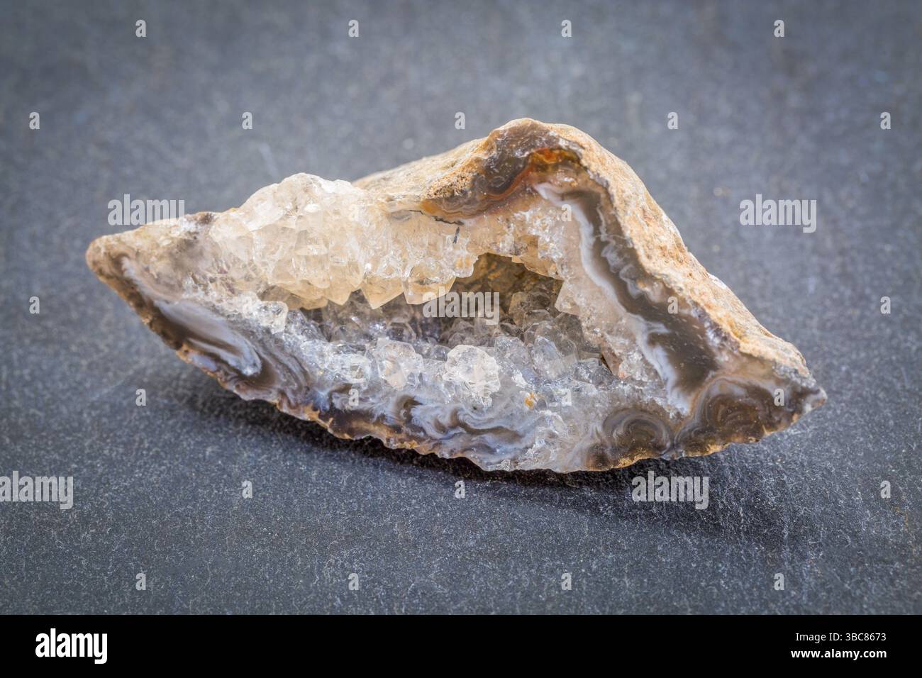Weiße und goldene Quarzgeode gegen grauen Schieferstein Stockfoto