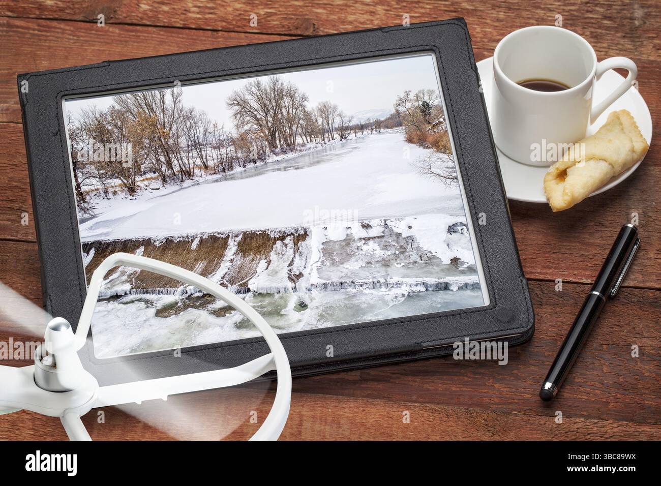 Wasserumleitung Luftbildkonzept - Überprüfung von Bildern von einem Damm und Fluss auf einem Tablet mit einer Drohne und Kaffee, Bildschirmbild Copyright by t Stockfoto
