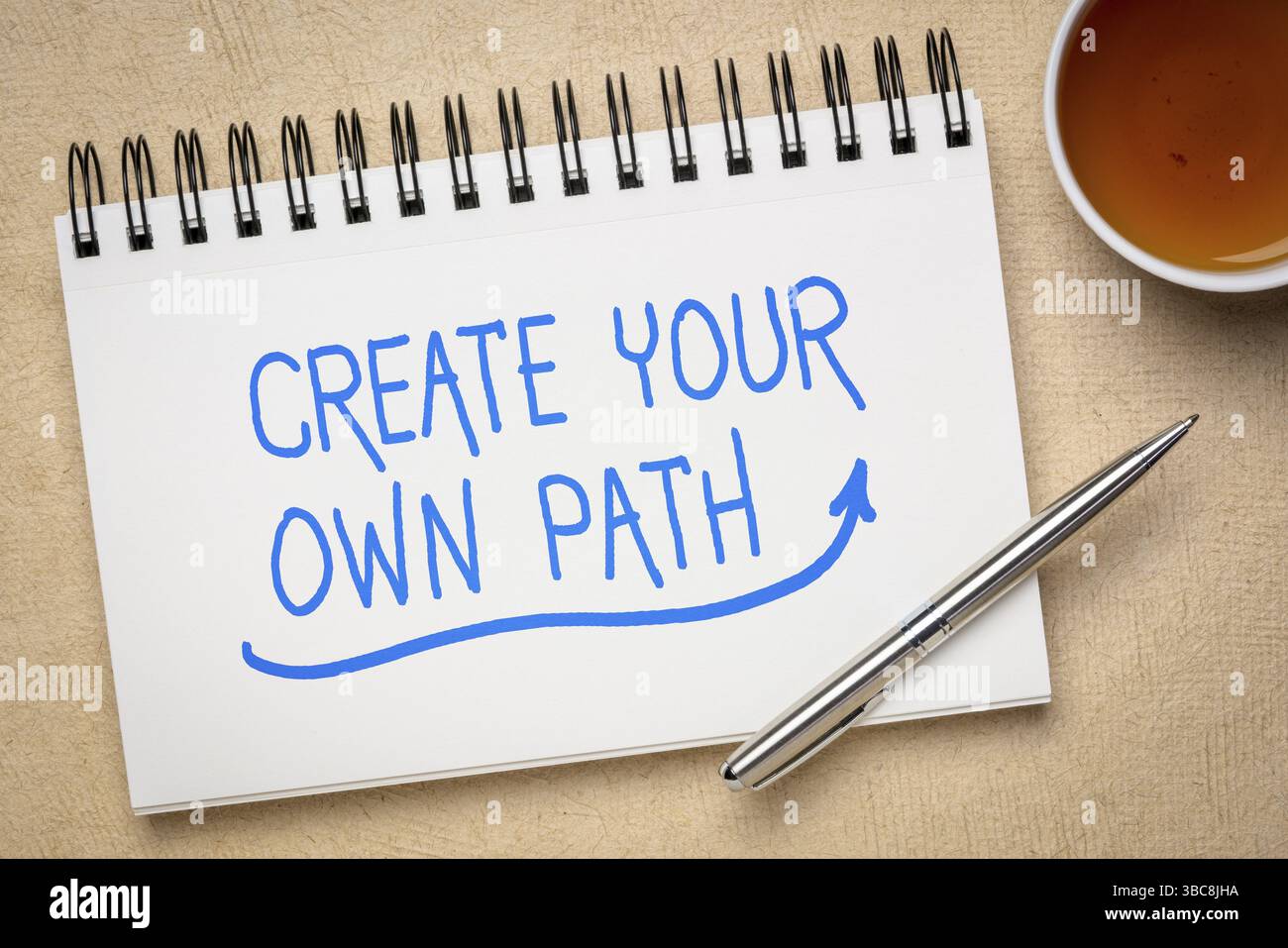 Erstellen Sie Ihren eigenen Weg inspirierendes Zitat – Handschrift auf einem Skizzenbuch mit einer Tasse Tee, Karriere und persönlichem Entwicklungskonzept Stockfoto