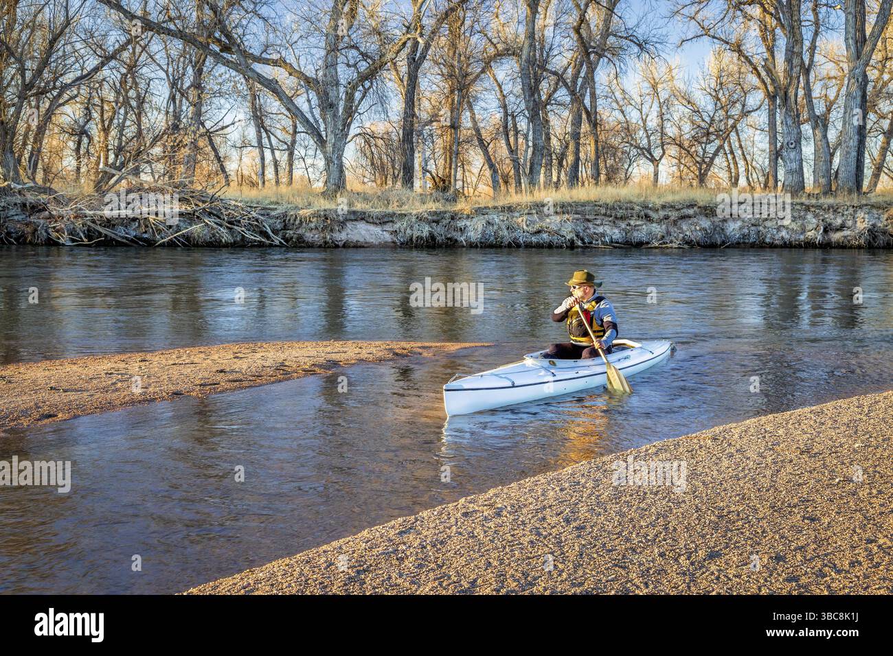 Senior Paddler in einem überdachten Expeditionskanu auf dem South Platte River im Osten Colorados, Winterlandschaft ohne Schnee Stockfoto