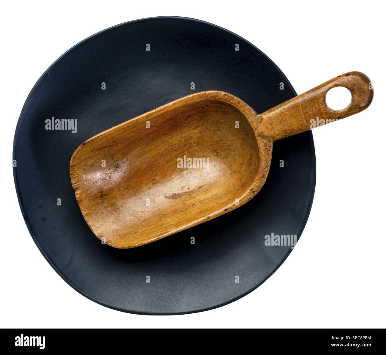 Leere rustikale Holzlöffel auf einer schwarzen Keramikplatte mit unregelmäßiger Kante isoliert auf weiß Stockfoto