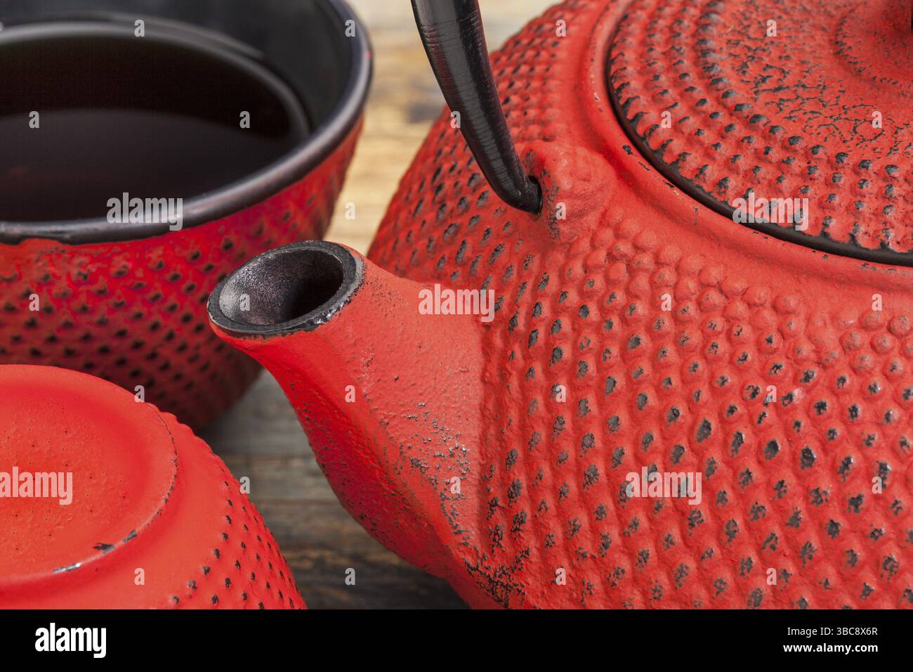 Rotes Tetsubin mit einer Tasse Tee - ein Detail einer traditionellen gusseisernen japanischen Teekanne Stockfoto