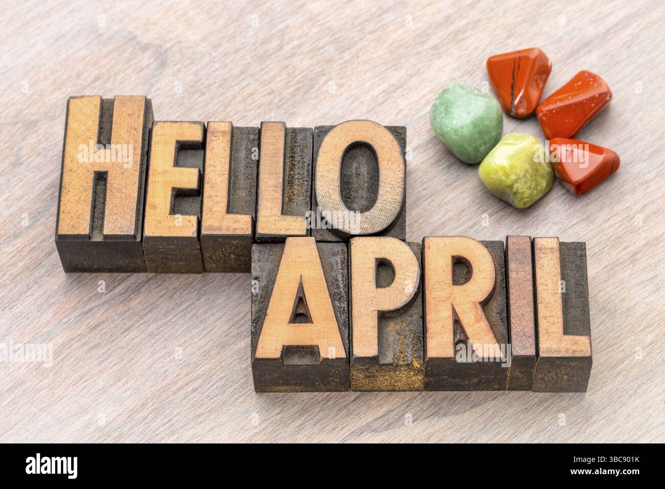 Hallo April in Vintage Letterpress Holzart mit grünen und roten Edelsteinkristallen Stockfoto