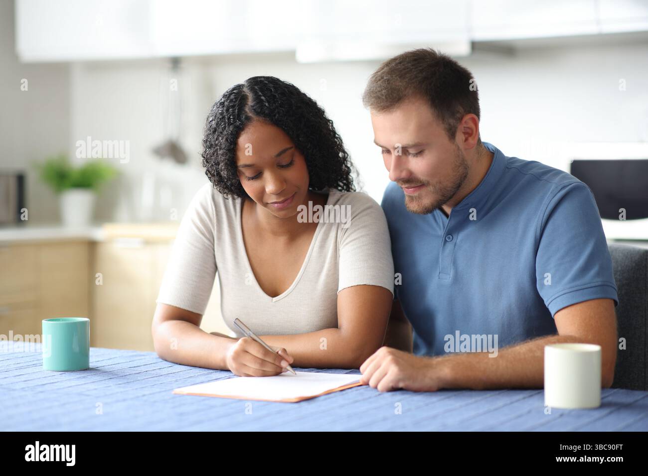 Interrassisches Paar unterschreibt Mietvertrag in der Küche zu Hause Stockfoto