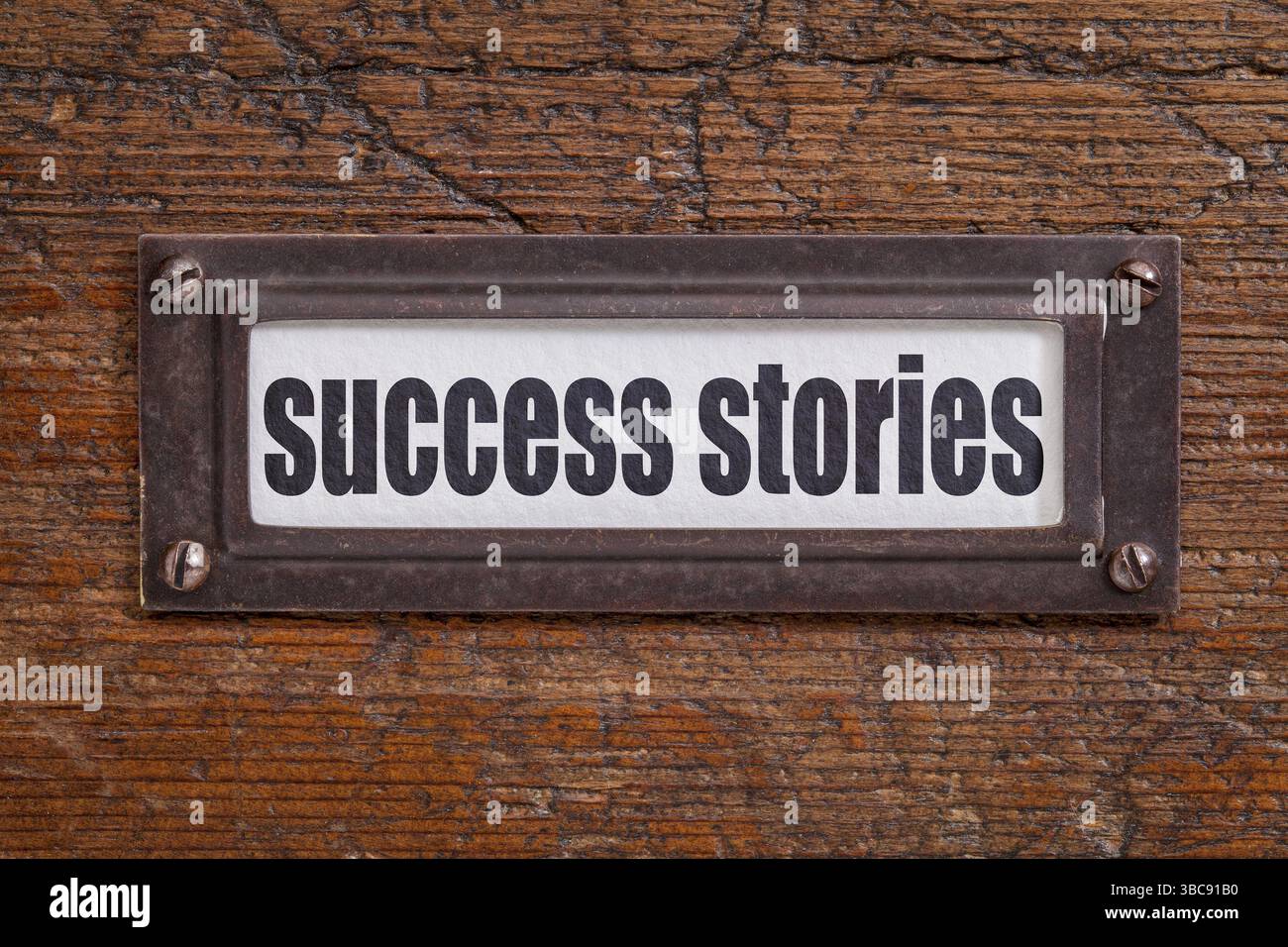 Erfolgsgeschichten - Aktenschranketikett, Bronzehalter gegen Schmirgel und zerkratztes Holz Stockfoto