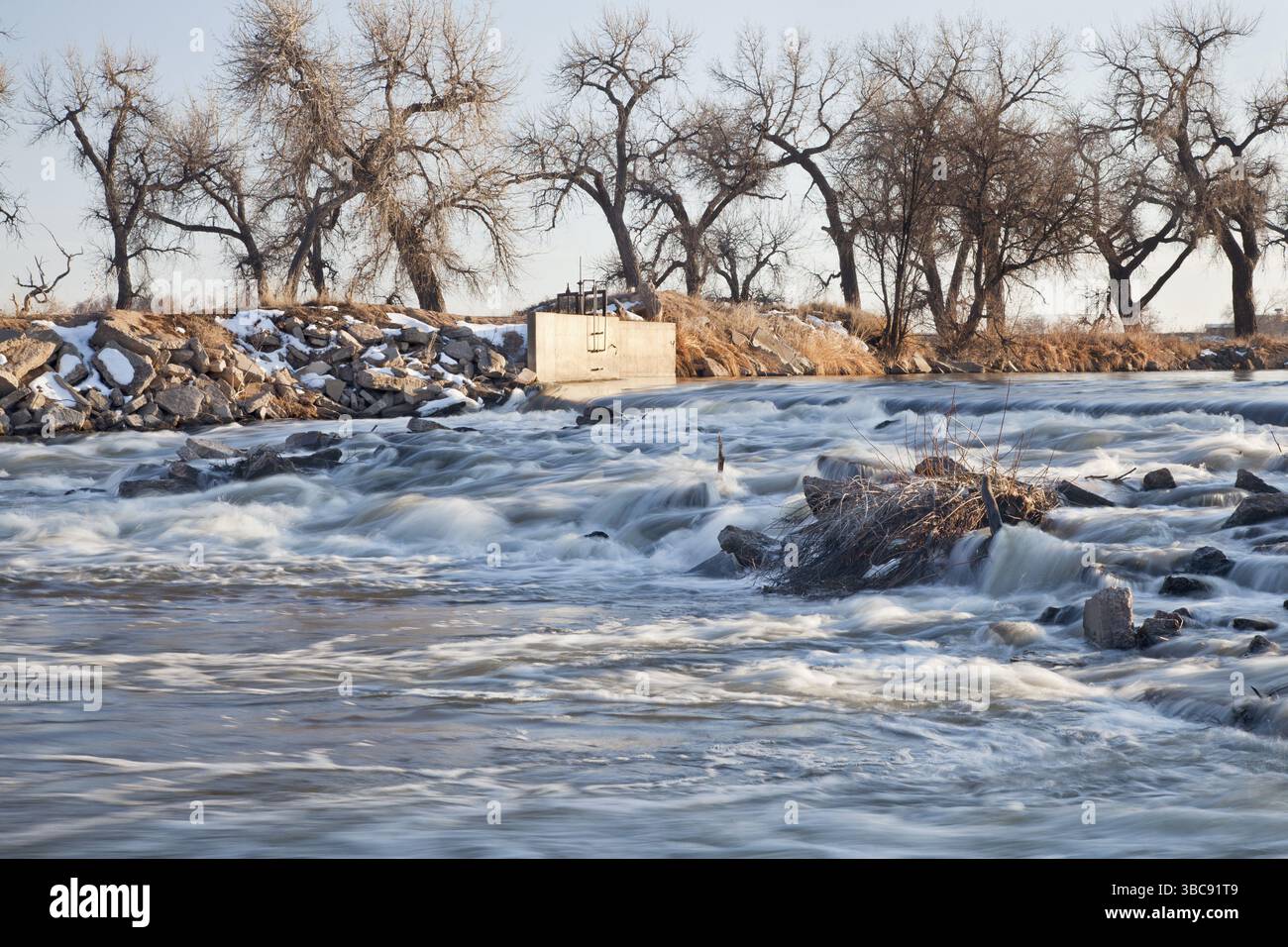 Ein kleiner Damm, der Wasser zur Bewässerung von Ackerland umleitet, South Platte River im Osten von Colorado bei Greeley, Winterlandschaft Stockfoto