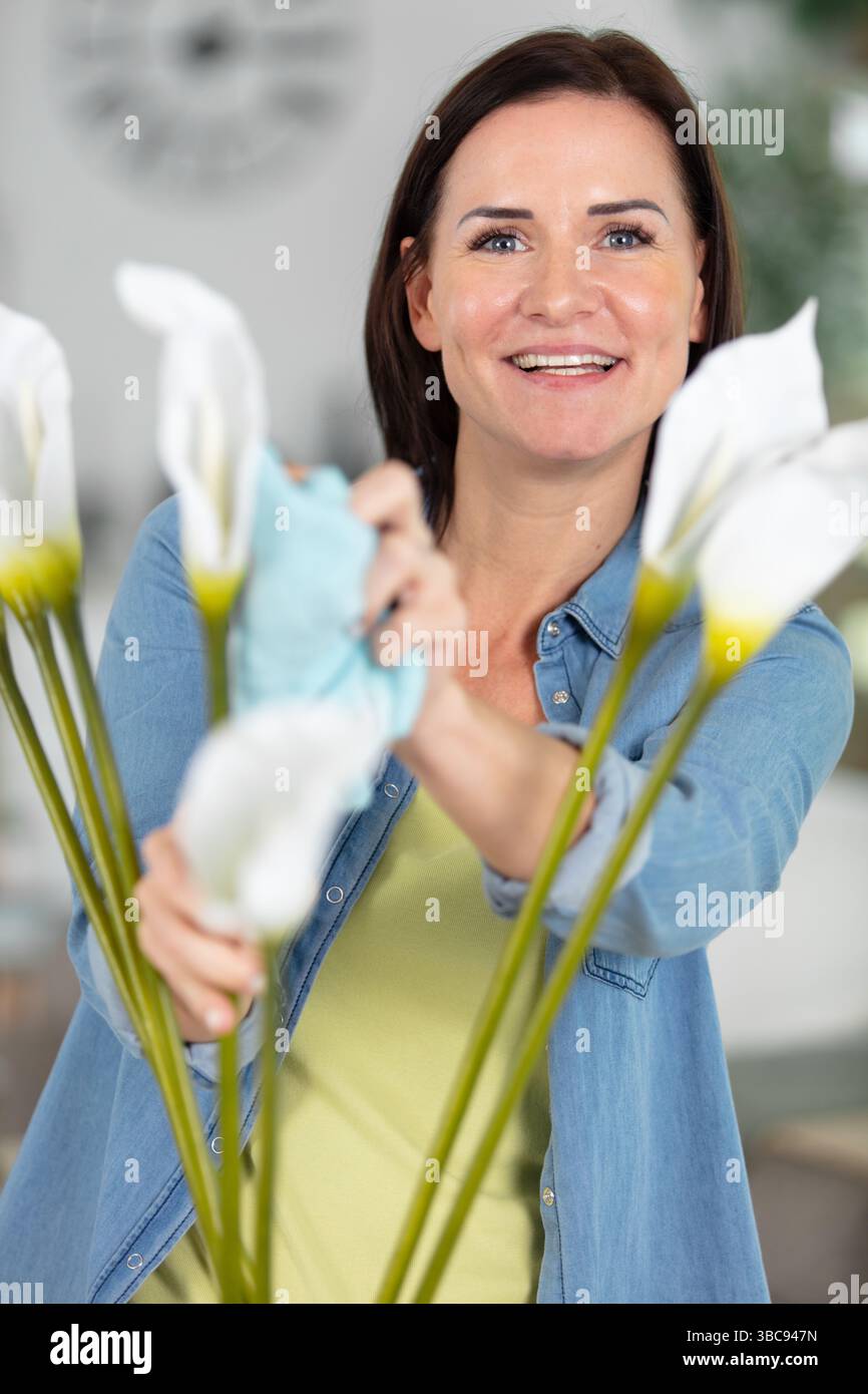 Reife Frau staubt Hauspflanzen ab Stockfoto