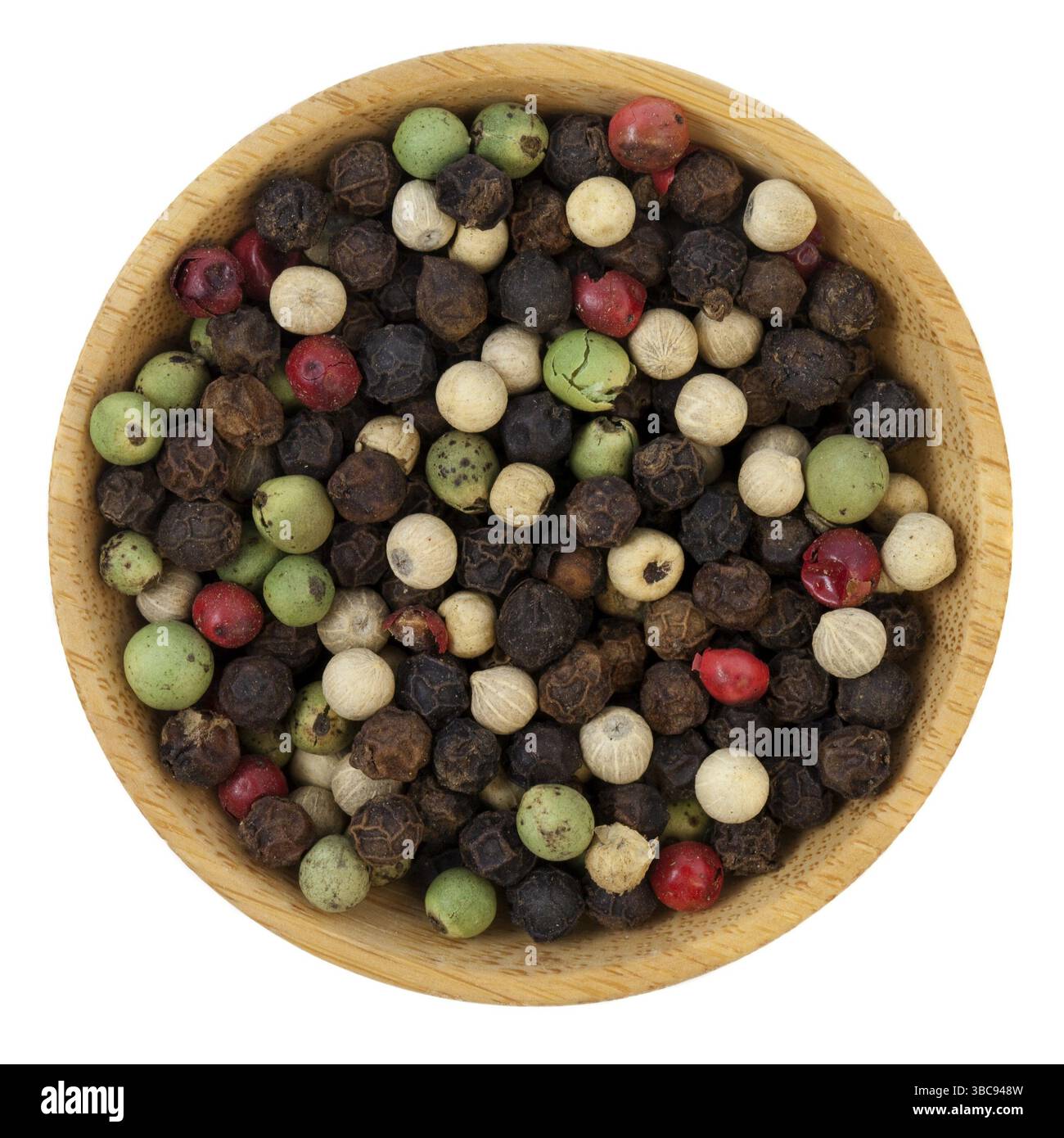 Mischung aus vier hochwertigen Paprika - Tellicherry Black, Madagaskar Green, malaysisches weiß und Ostindisches Pink auf einer kleinen Holzschale, isoliert auf weiß Stockfoto