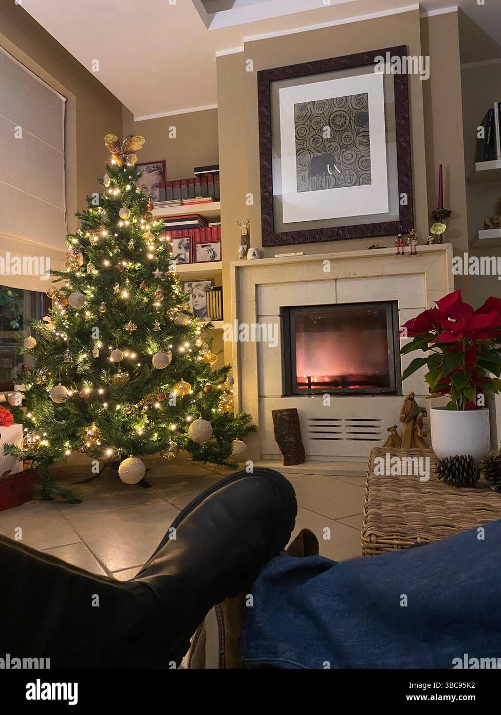 Mann, der während der Weihnachtsferien in Pineto, Italien, am Kamin in gemütlicher heimischer Umgebung entspannt und die Wärme und festliche Atmosphäre genießt Stockfoto