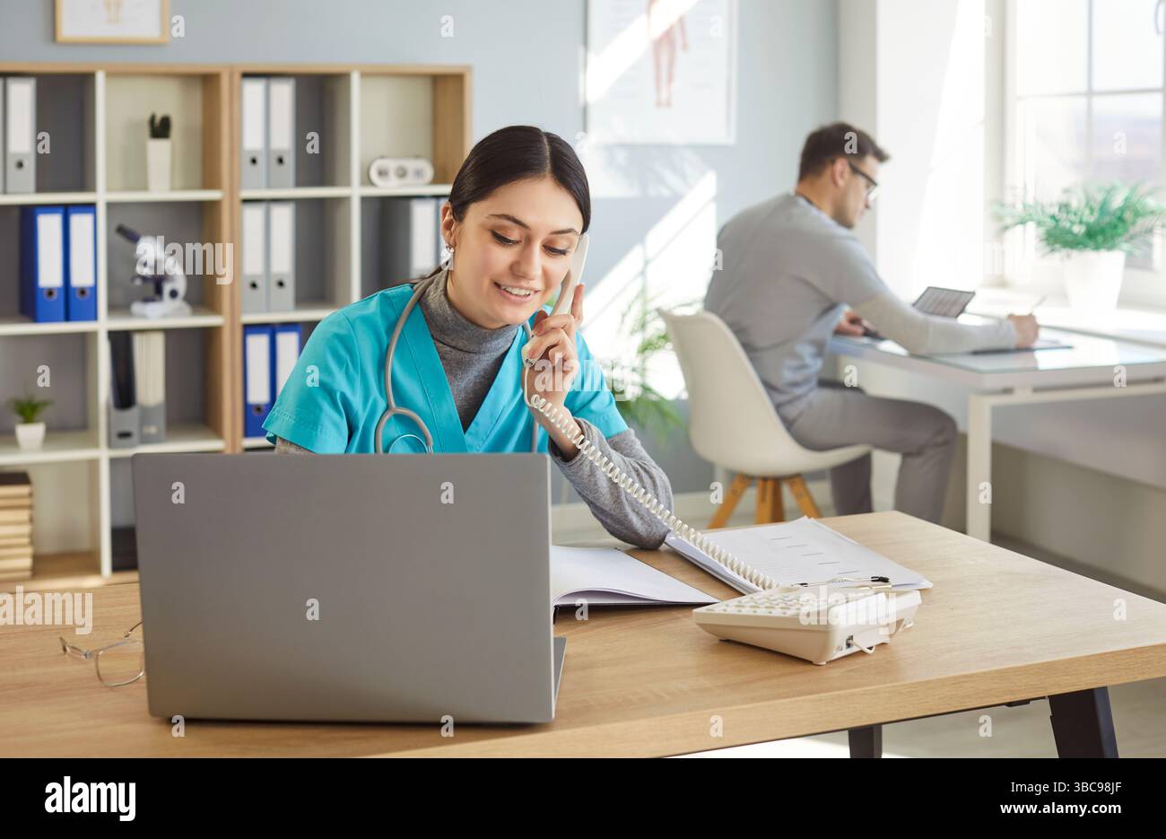 Freundliche weibliche Krankenschwester-Rezeptionistin, die Telefonanrufe entgegennimmt, Termine vereinbart Stockfoto