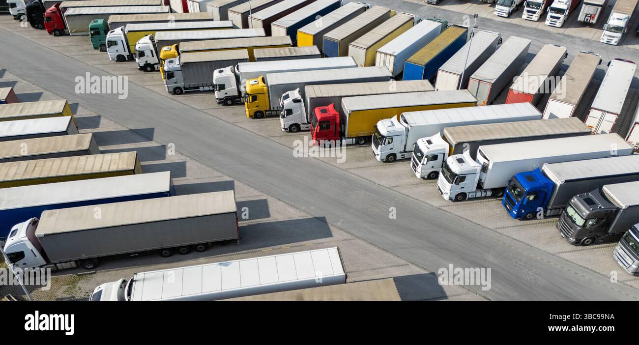 Aus der Vogelperspektive eines großen LKW-Parkplatzes an einem Logistikzentrum mit mehreren gewerblichen Sattelzügen, die in organisierten Reihen geparkt sind. Stockfoto