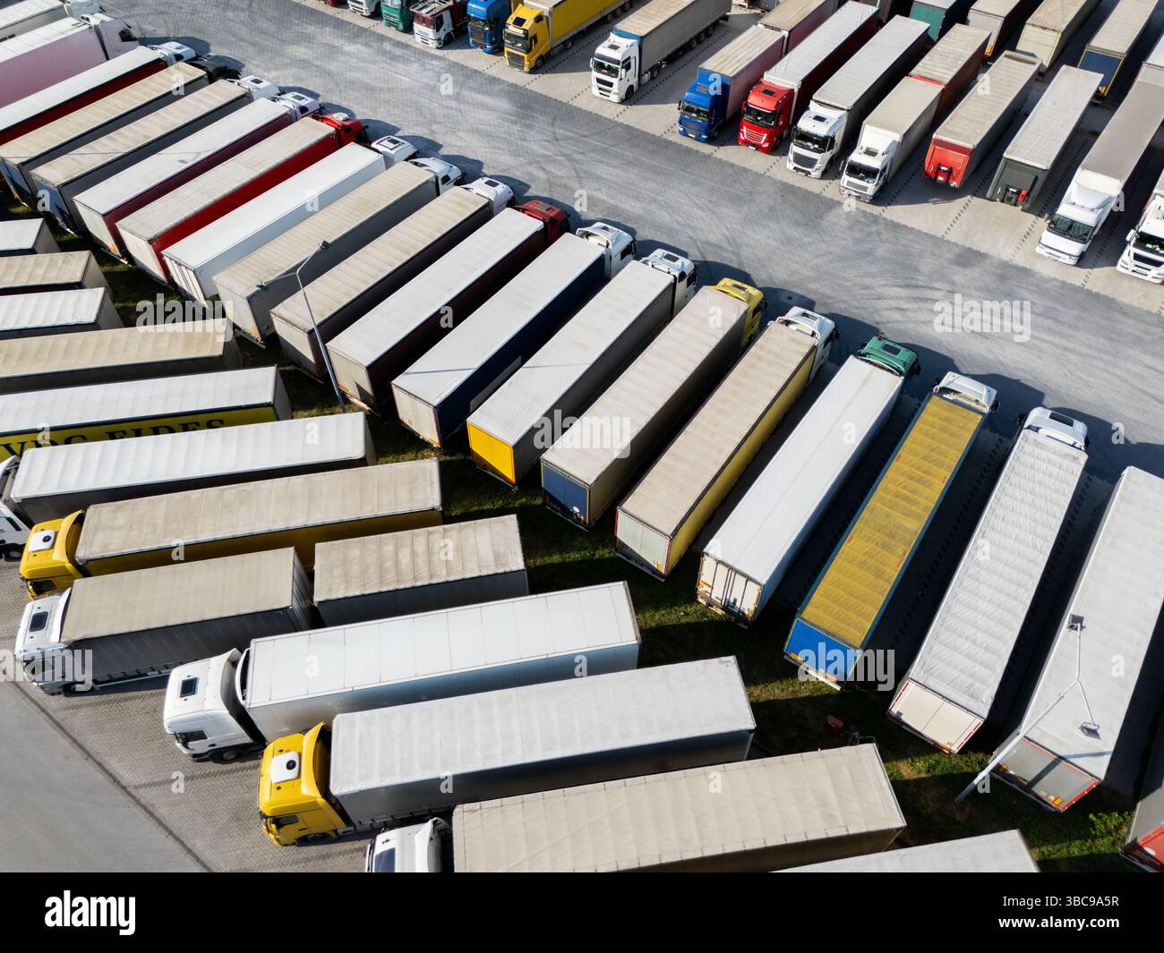 Aus der Vogelperspektive eines großen LKW-Parkplatzes an einem Logistikzentrum mit mehreren gewerblichen Sattelzügen, die in organisierten Reihen geparkt sind. Stockfoto