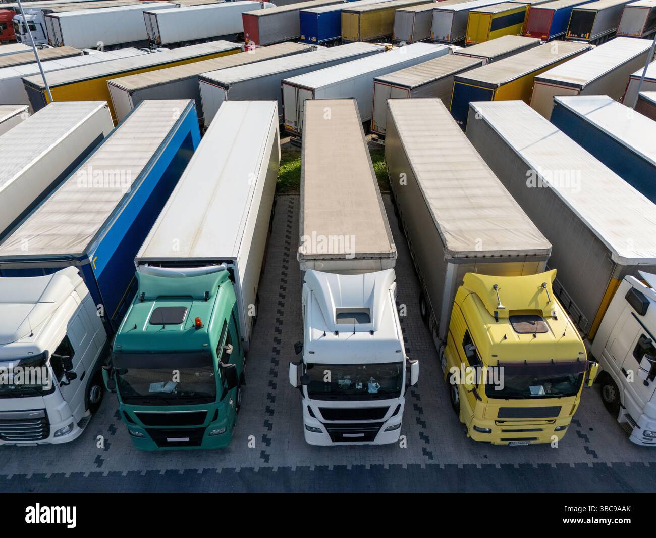 Aus der Vogelperspektive eines großen LKW-Parkplatzes an einem Logistikzentrum mit mehreren gewerblichen Sattelzügen, die in organisierten Reihen geparkt sind. Stockfoto