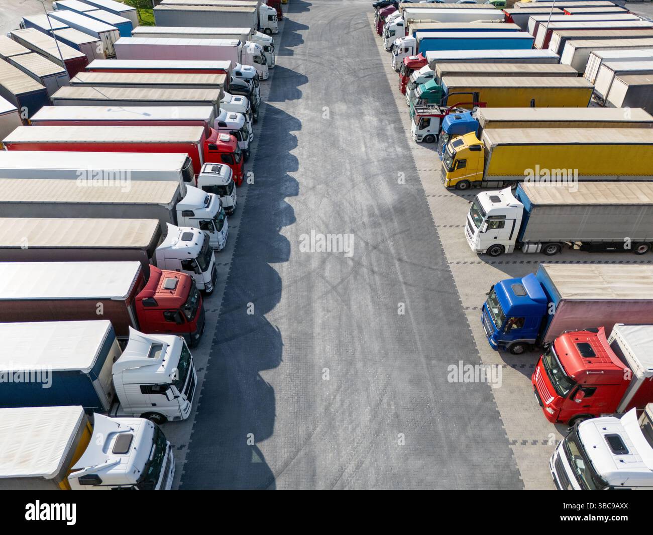 Aus der Vogelperspektive eines großen LKW-Parkplatzes an einem Logistikzentrum mit mehreren gewerblichen Sattelzügen, die in organisierten Reihen geparkt sind. Stockfoto