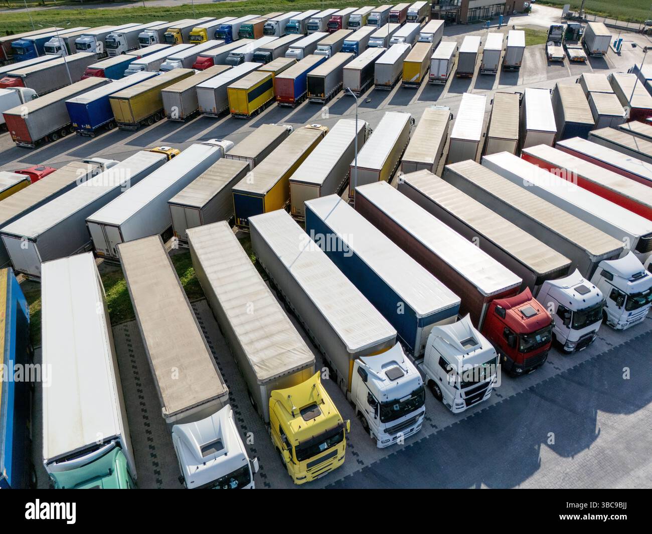 Aus der Vogelperspektive eines großen LKW-Parkplatzes an einem Logistikzentrum mit mehreren gewerblichen Sattelzügen, die in organisierten Reihen geparkt sind. Stockfoto