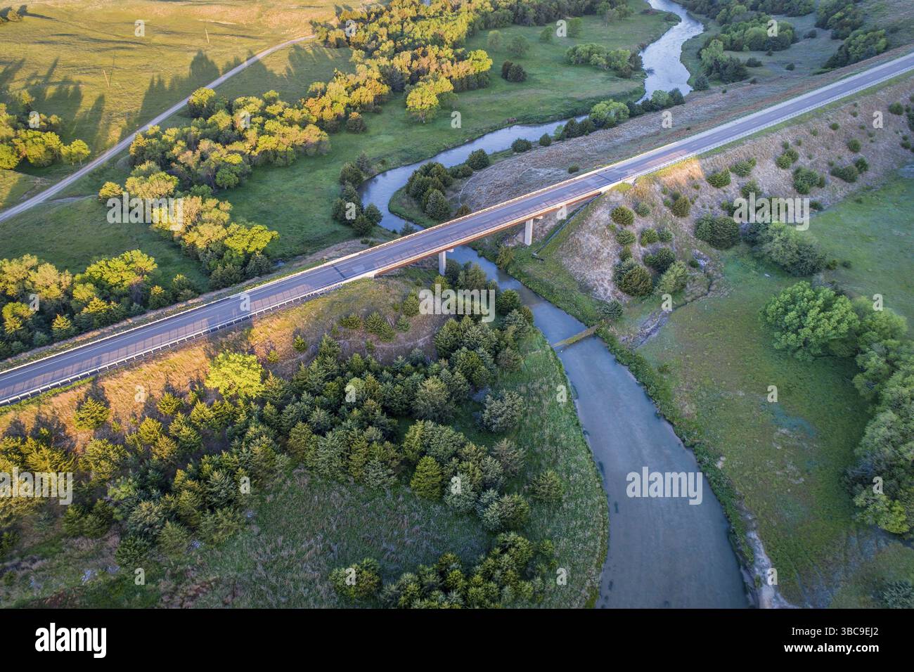 Aus der Vogelperspektive auf eine Autobahn und eine Brücke über den Dismal River in Nebraska Sandhills in der Nähe von Thedford, Frühlingslandschaft beleuchtet von Sonnenaufgangslicht Stockfoto
