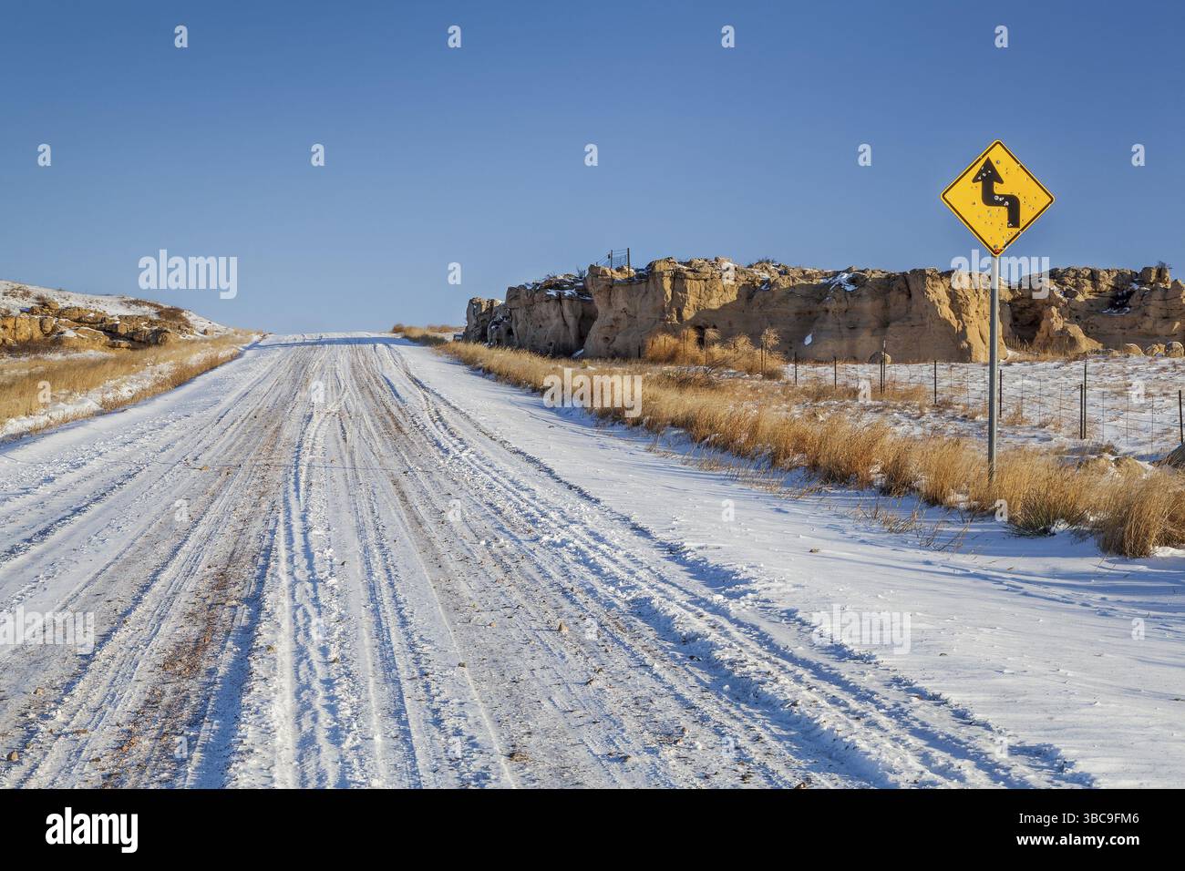 Hinterlandstraße über die Prärie im Norden Colorados im Winter, ein Straßenschild mit Schusslöchern Stockfoto