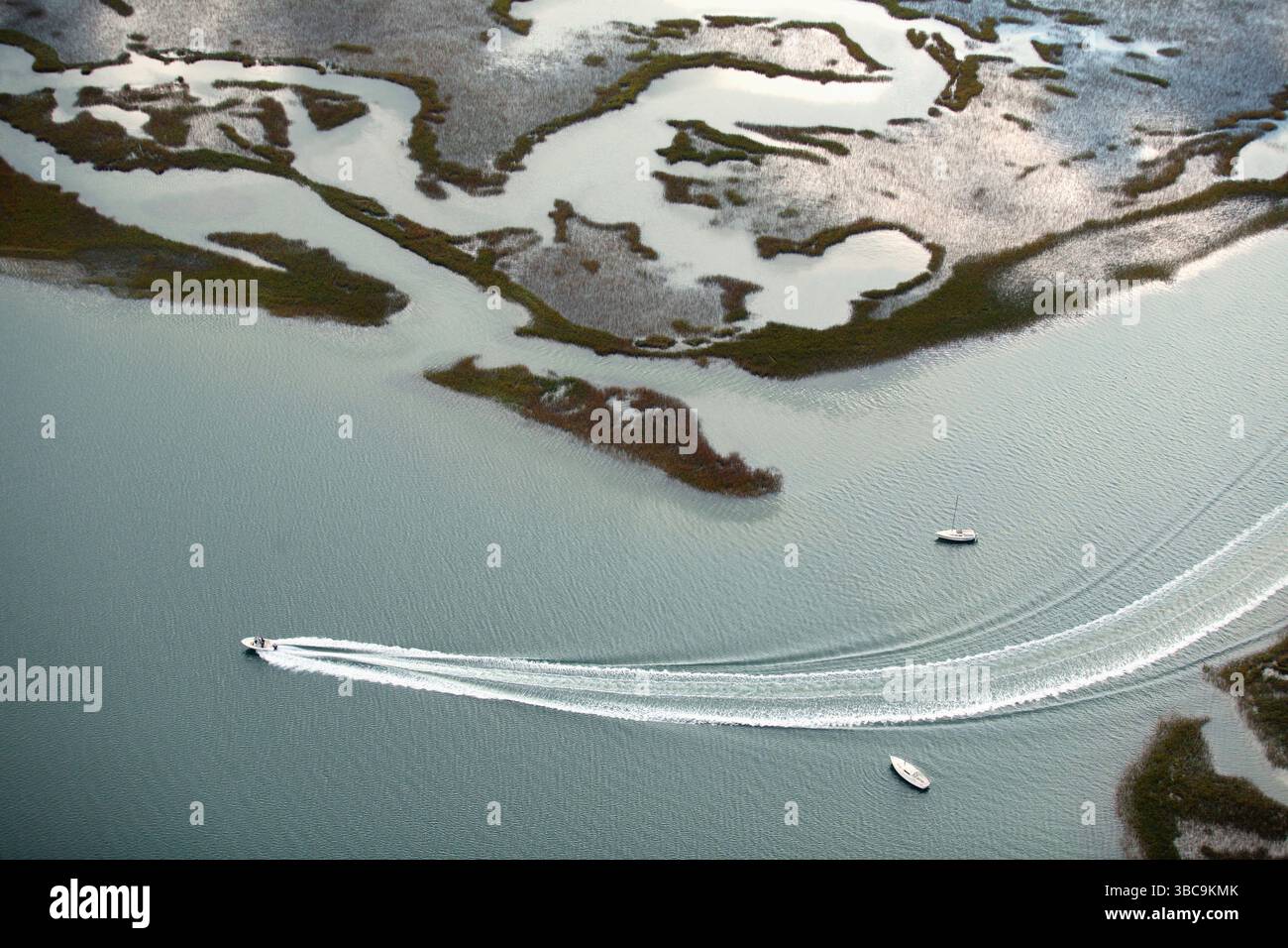 Luftaufnahme eines Motorbootes, das zwischen Segelbooten in der Nähe von Sümpfen und Barriereinseln um Wrightsville Beach, NC, fährt Stockfoto