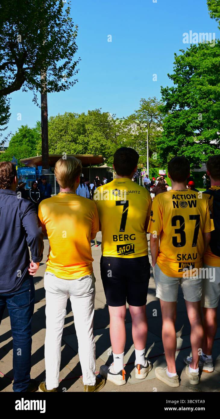 Eine Gruppe von Jungen, die hinter der Kamera eine Veranstaltung in der South Bank in London anschauen, in gelben Hemden mit norwegischem Motiv. Stockfoto