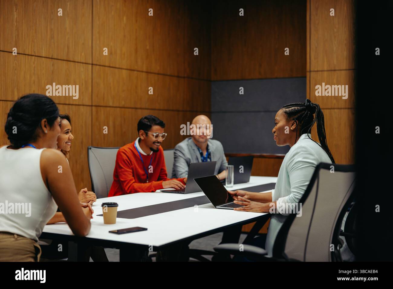 Ein geschäftliches Meeting mit einem vielfältigen Team, das Ideen an einem Sitzungstisch diskutiert. Die Gruppe besteht aus fünf engagierten Fachleuten und Colla Stockfoto