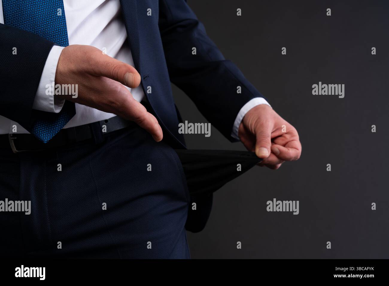 Zugeschnittene Ansicht eines Geschäftsmannes in marineblauem Anzug und blauer Krawatte, der eine leere Tasche als Symbol für finanzielle Not oder Konkurs herauszieht. Stockfoto