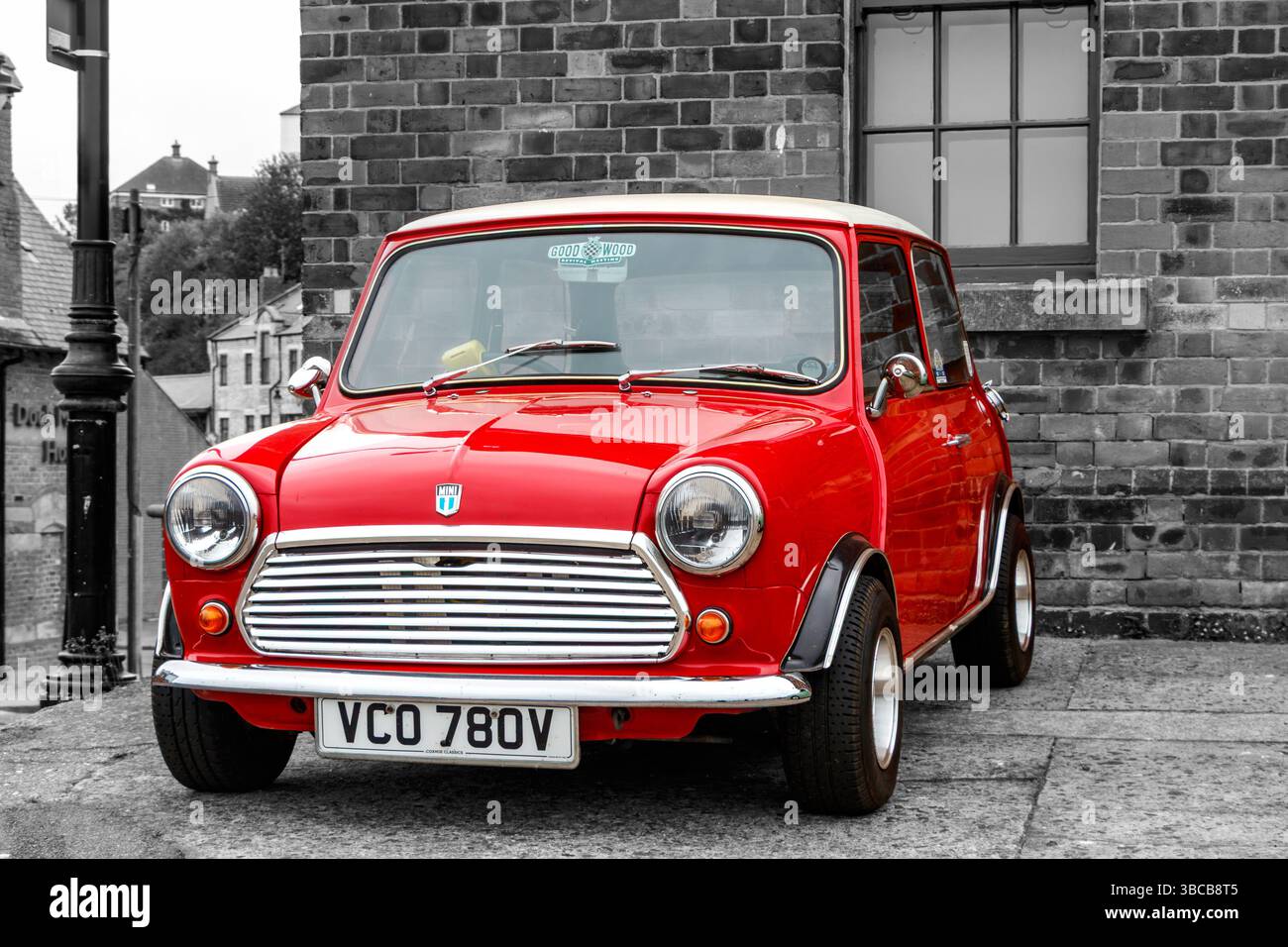 Ein leuchtend roter klassischer Mini Cooper mit weißem Dach, schwarz-weißem Hintergrund der Gebäude. In den nördlichen Schilden Stockfoto