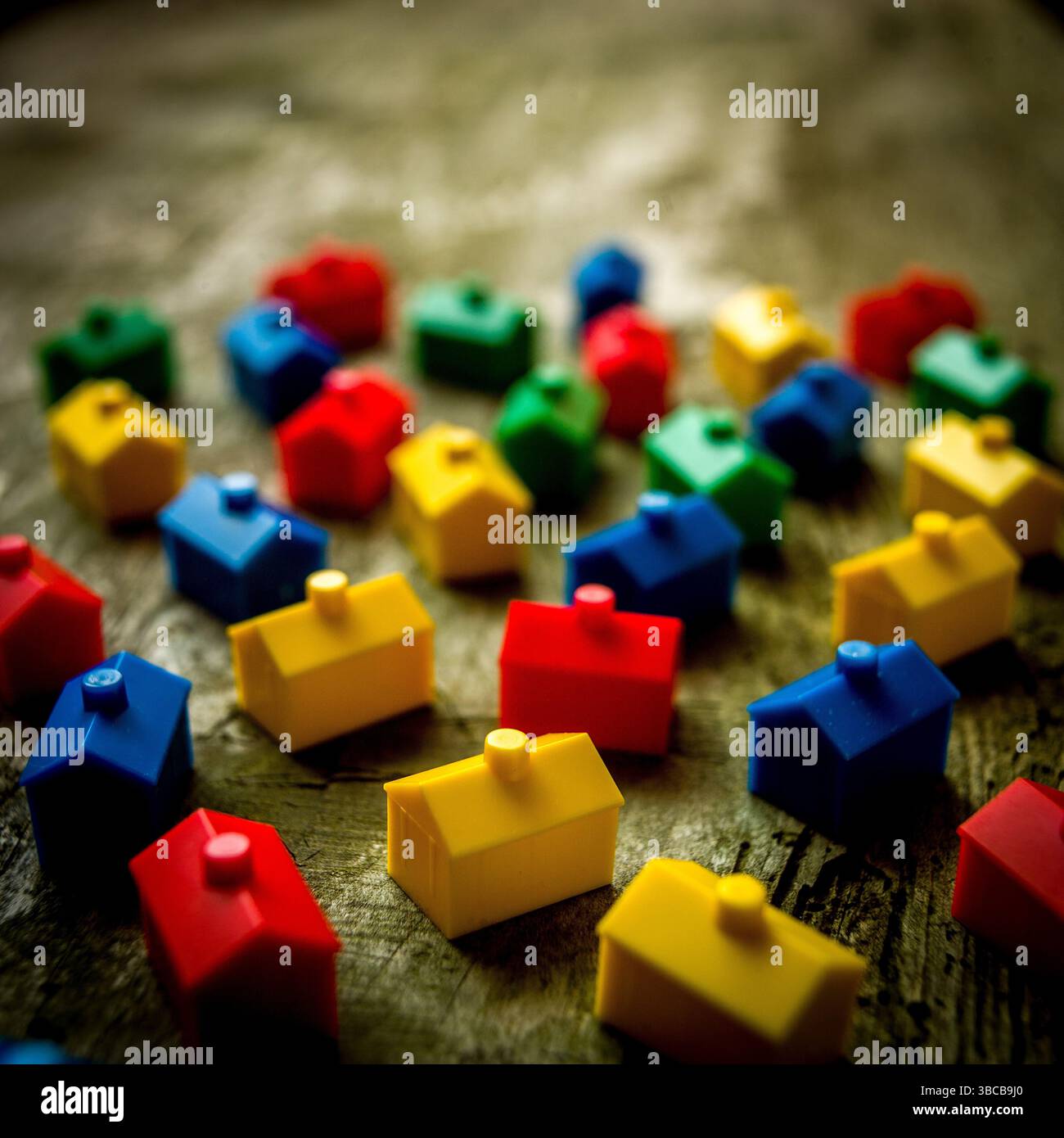 Zahlreiche kleine Häuser in hellen Farben sind auf einer strukturierten Holzoberfläche angeordnet, die eine lebhafte Atmosphäre erzeugt, die an klassische Brettspiele erinnert Stockfoto