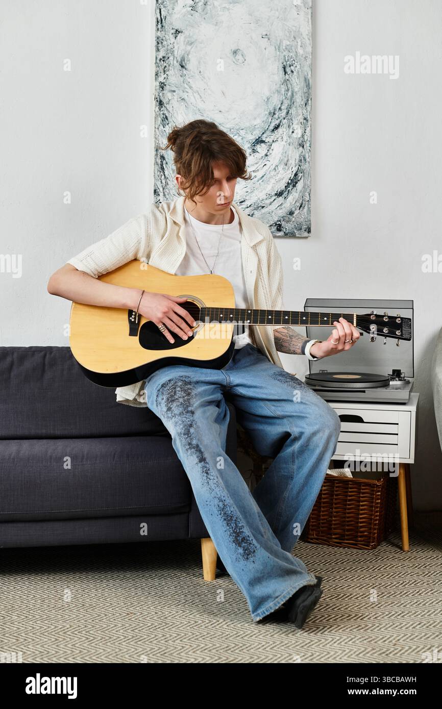Ein junger Schüler erkundet sein musikalisches Talent zu Hause an einem gemütlichen Nachmittag mit einer Gitarre. Stockfoto