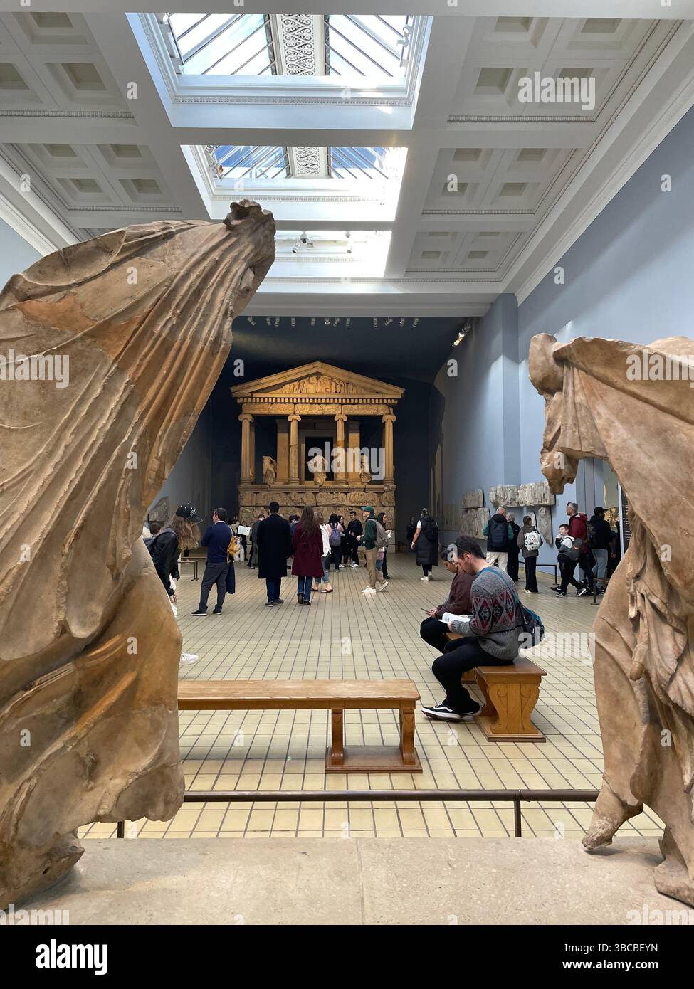 Besucher erkunden die Galerie mit dem Nereid Monument im British Museum in London, eingerahmt von anmutigen antiken griechischen Skulpturen. Stockfoto
