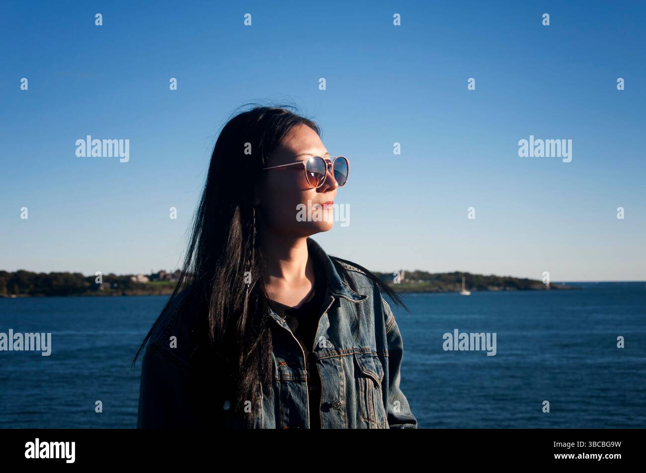 Eine chinesin mit Sonne im Gesicht im Fort Wetherill State Park in Jamestown, Rhode Island. Stockfoto