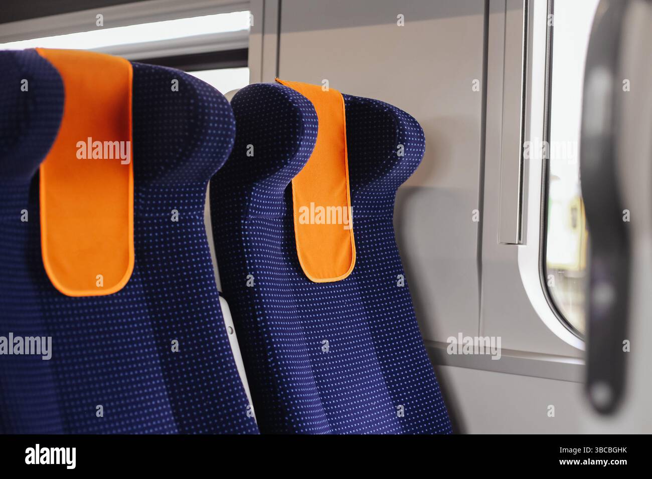 Moderne Innenausstattung der Züge. Bequeme Beifahrersitze. Blaue Polsterung mit orangefarbenen Kopfstützen. Öffentliche Verkehrsmittel in Europa. Leerer Zug. Stockfoto