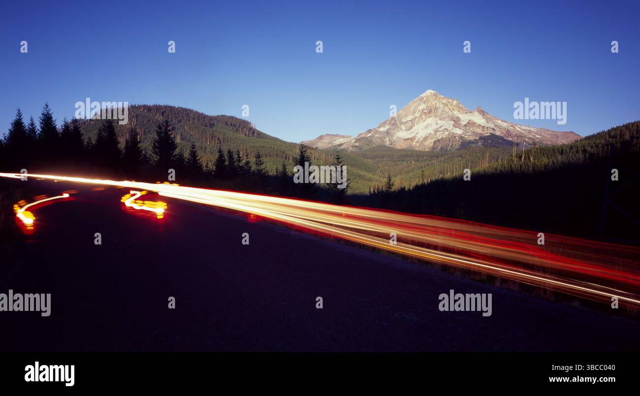 Eine Doppelbelichtung, bei der Autolichter unter dem Mt Hood in Zentral-Oregon vorbeifahren. Stockfoto