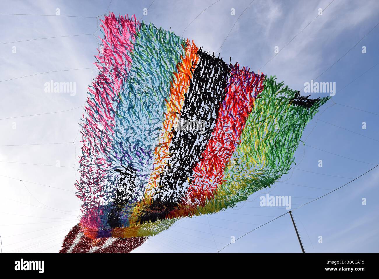 Sky Woven with Color: Ein glitzerndes Baldachin aus flatternden Bändern verwandelt die Luft in ein Meisterwerk aus Bewegung und Licht Stockfoto