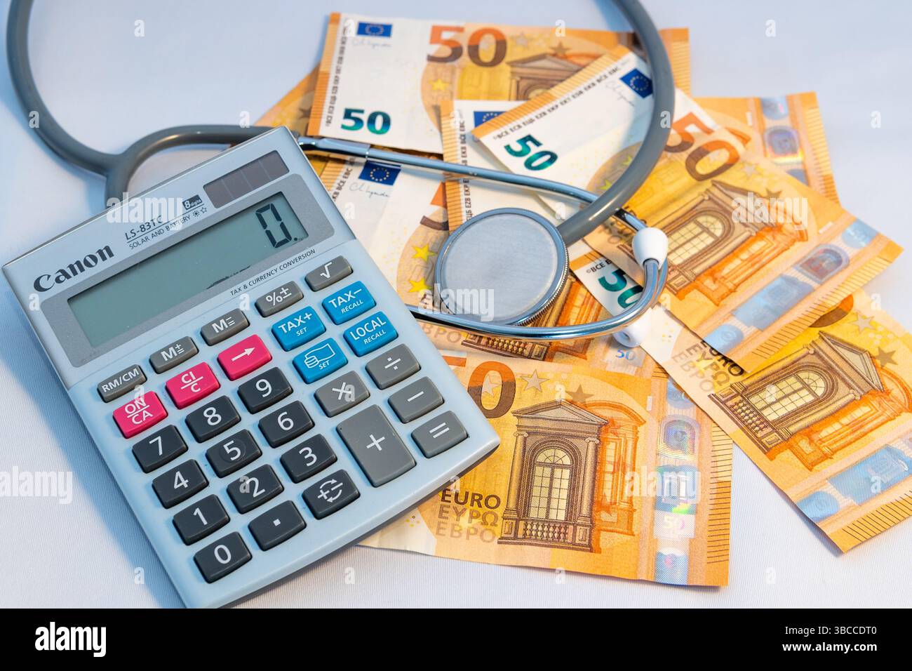 Stethoskop und Taschenrechner auf €50 Banknoten auf weißem Hintergrund. Stockfoto