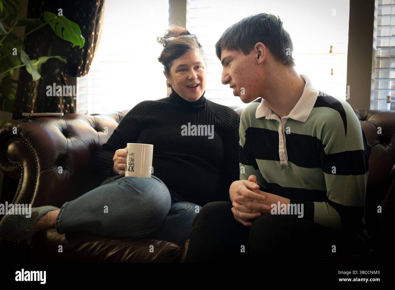 Ft. Mill, South Carolina, USA. März 2025. Beth Hodges genießt˜Kaffeezeit mit ihrem 19-jährigen Sohn Jack, während sie auf einen Bus zu einer speziellen Schule für Kinder mit Entwicklungsbehinderungen warten. Jack hat einen seltenen Krampfanfall namens Dravet-Syndrom, sowie Autismus der Stufe 3. (Kreditbild: © Robin Rayne/ZUMA Press Wire) NUR REDAKTIONELLE VERWENDUNG! Nicht für kommerzielle ZWECKE! Stockfoto
